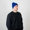 A man wearing a royal blue unisex merino wool beanie; the elastic one-size-fits-all design perfectly contours to the head for maximum comfort.