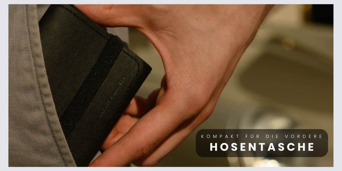 Schwarzes kleines Portemonnaie für Herren, das in eine vordere Hosentasche gesteckt wird.